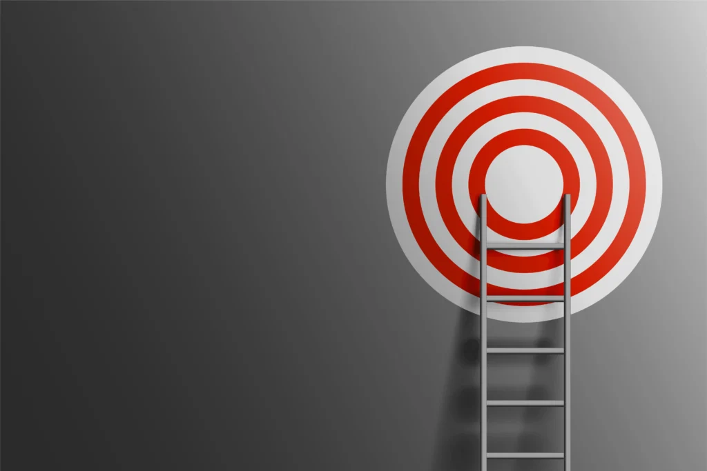 Ladder leaning on a red bullseye target on a gray wall, symbolizing clear goals and focus