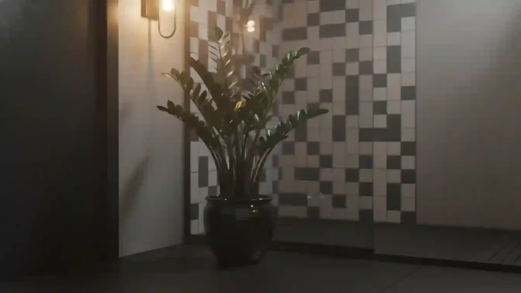 glossy zz plant in a dark pot beside a tiled shower corner giving rich green contrast on yourselflovehub.com